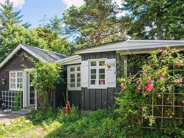 A rustic wooden house with a small porch and a window with shutters.