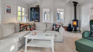 A cozy living room with a white sofa, a coffee table, a green armchair, and a wood-burning stove. - "Dorthea" - 200m from the sea by Interhome (Jerup)
