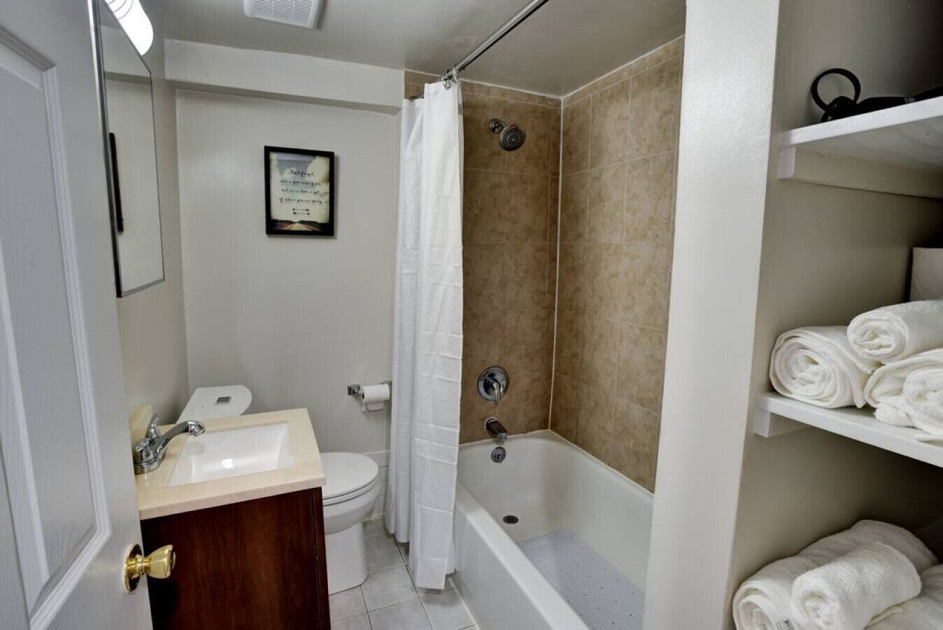 Een badkamer met een wastafel, toilet, douche en een handdoekhouder.