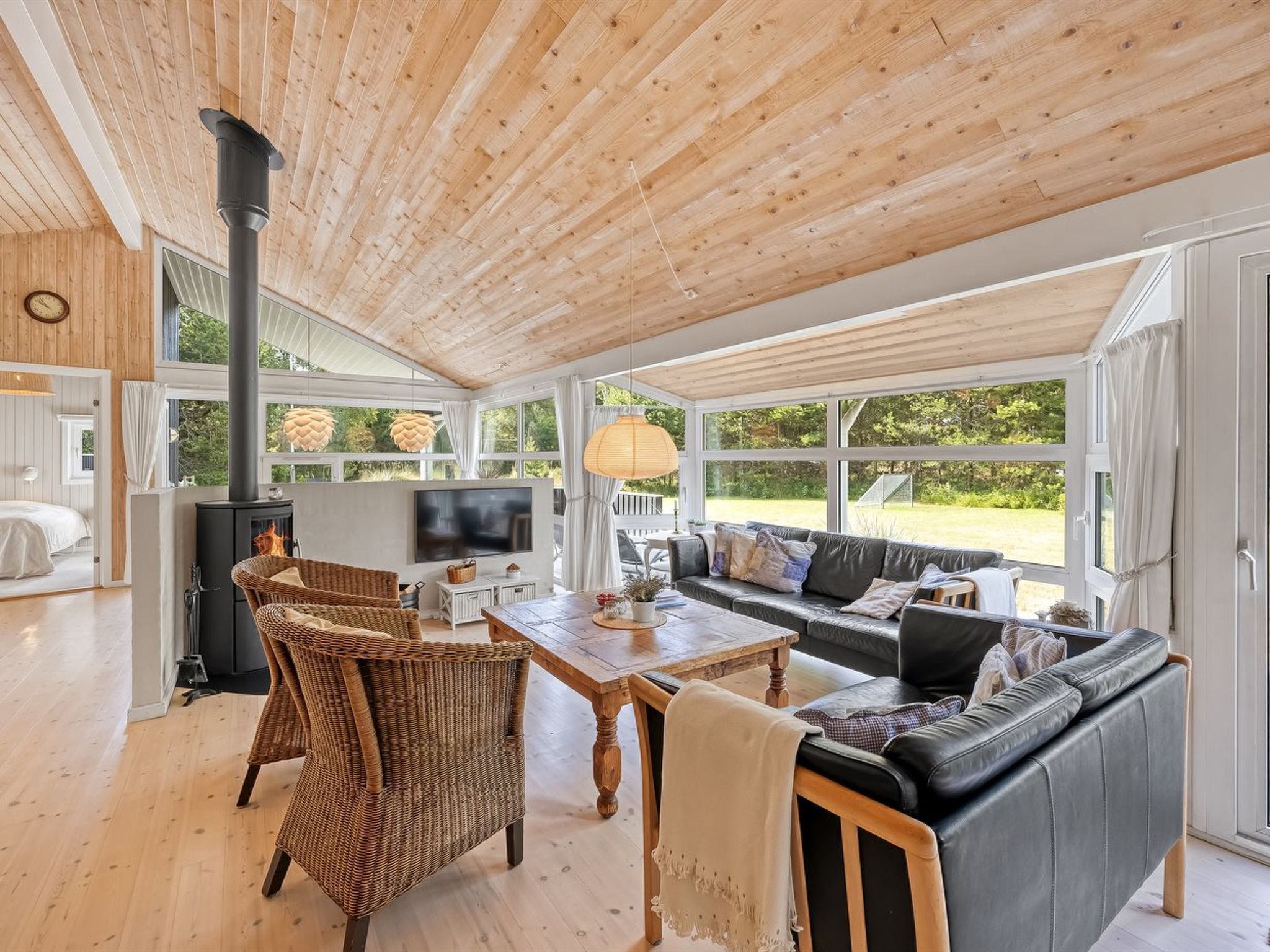 A spacious living area with a fireplace, a sofa, a dining table, and a television.