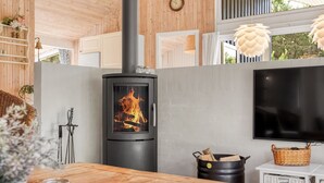 Een moderne keuken met een houtkachel, een flatscreen televisie en een eethoek met een houten tafel.