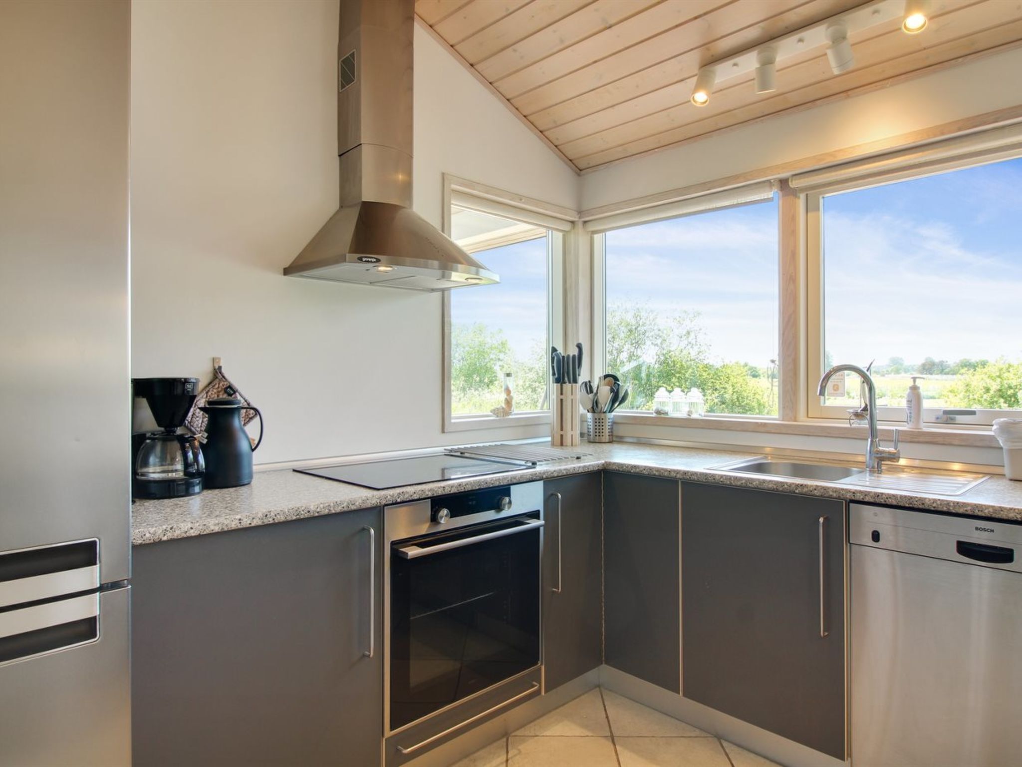 A modern kitchen with a built-in oven, a coffee maker, and a sink.