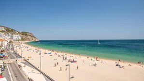 Una playa con vistas despejadas al mar, una orilla arenosa y un pueblo al fondo.