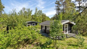 Twee vakantiehuisjes in een bebost gebied, met een terras en buitenmeubels.