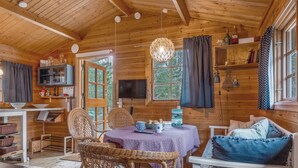 Een gezellig interieur van een vakantiehuisje, met een eethoek, een televisie en een zithoek met een bank en een stoel.