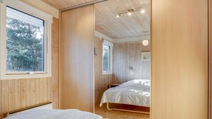 A room with wooden panel walls, a large window, and a bed with a white bedspread.