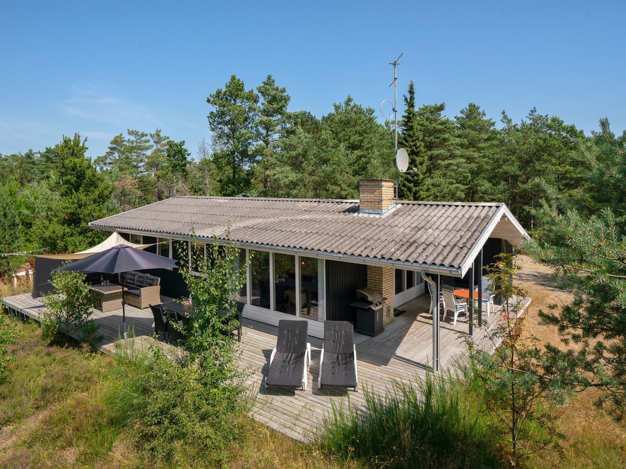 A modern house with a covered patio, outdoor furniture, and a satellite dish.