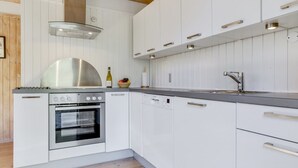 A modern kitchen with white cabinetry, stainless steel appliances, and a wooden ceiling.