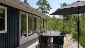 A deck with a table and chairs, a pergola, and a view of trees.