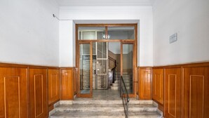 A grand staircase with wooden paneling and a marble floor leading to a glass door entrance. - Comfort Corner in Via Dante (Cagliari)