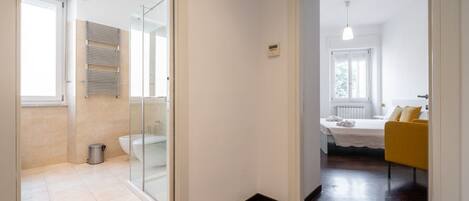 A modern bathroom with a glass shower enclosure, a toilet, and a towel rack.