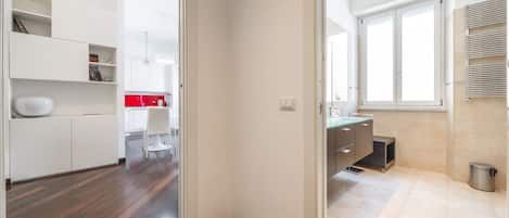 A modern kitchen with white cabinets, a red backsplash, and a large window providing natural light.