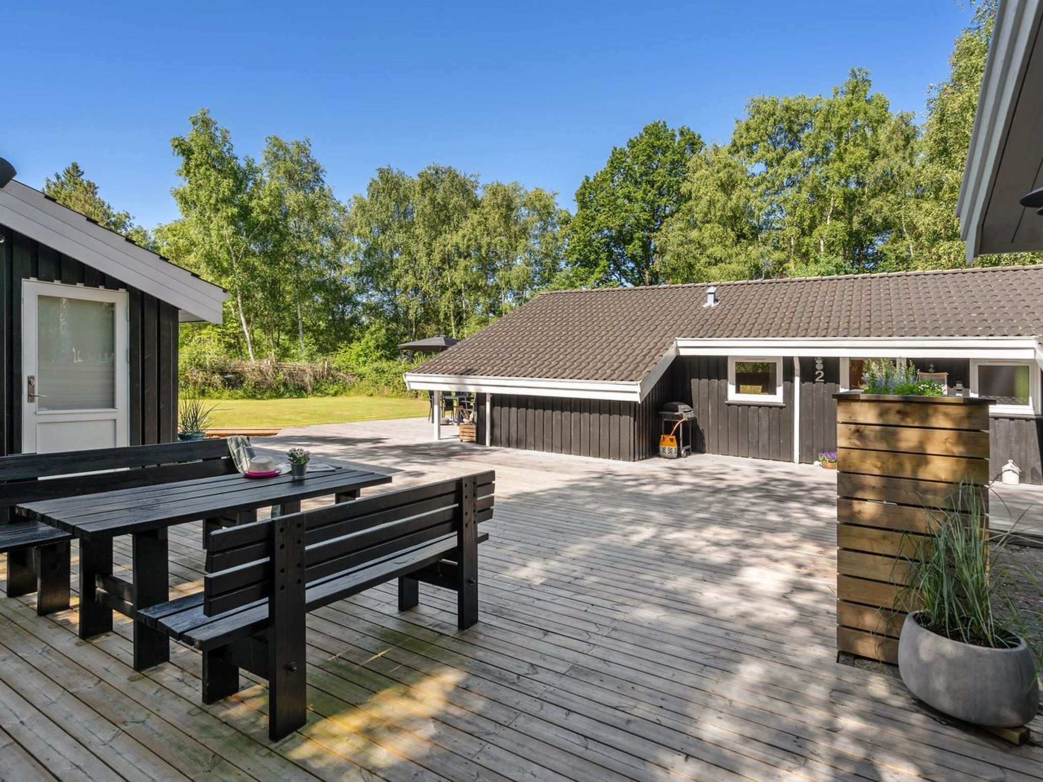 A wooden deck with outdoor seating and a covered area with a tiled roof.