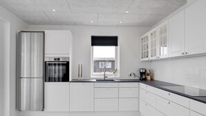 Una cocina moderna con armarios blancos, un refrigerador de acero inoxidable y una ventana con vistas al exterior.
