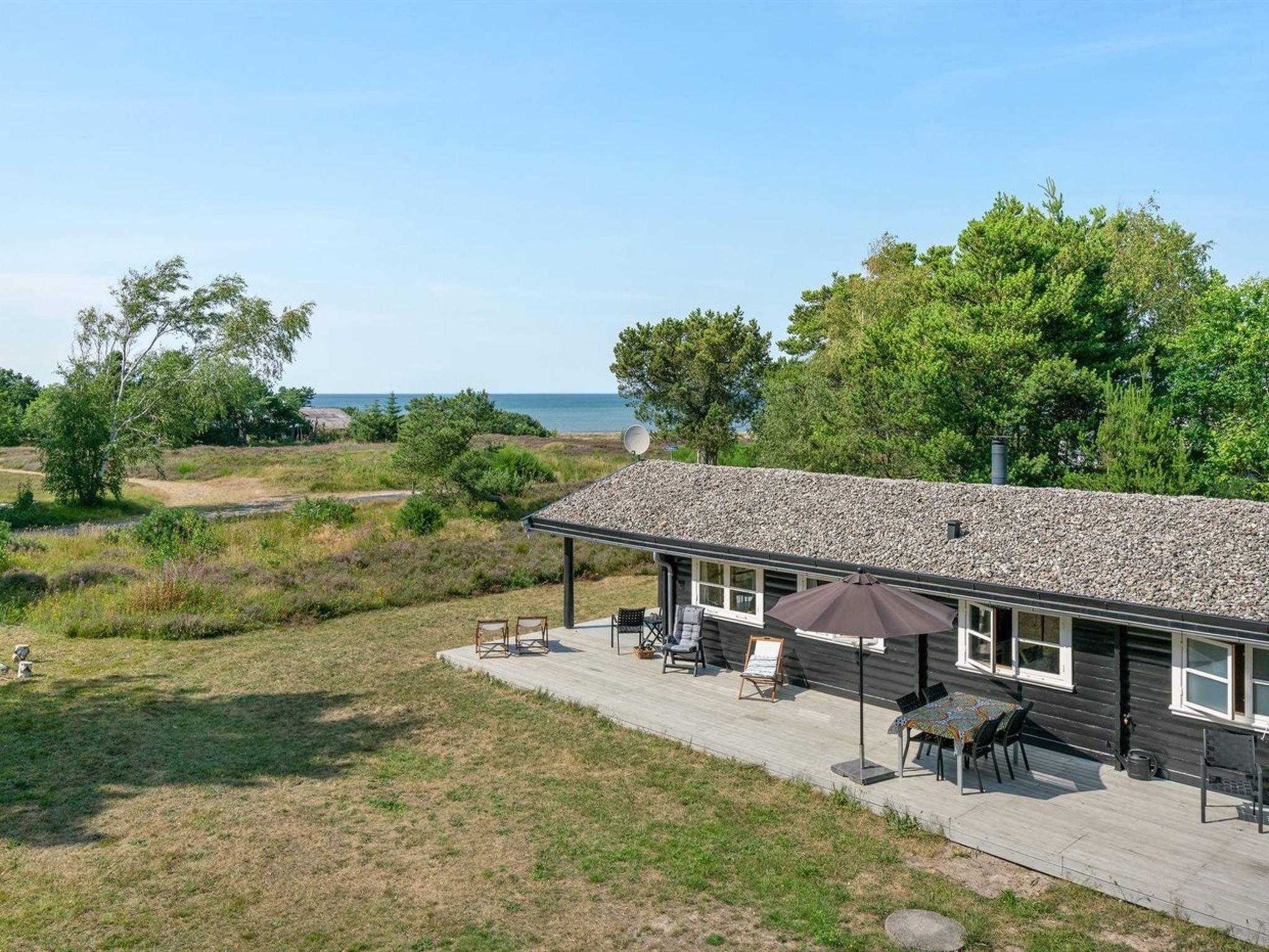 A cabin with a gravel roof, outdoor seating, and a view of the ocean.