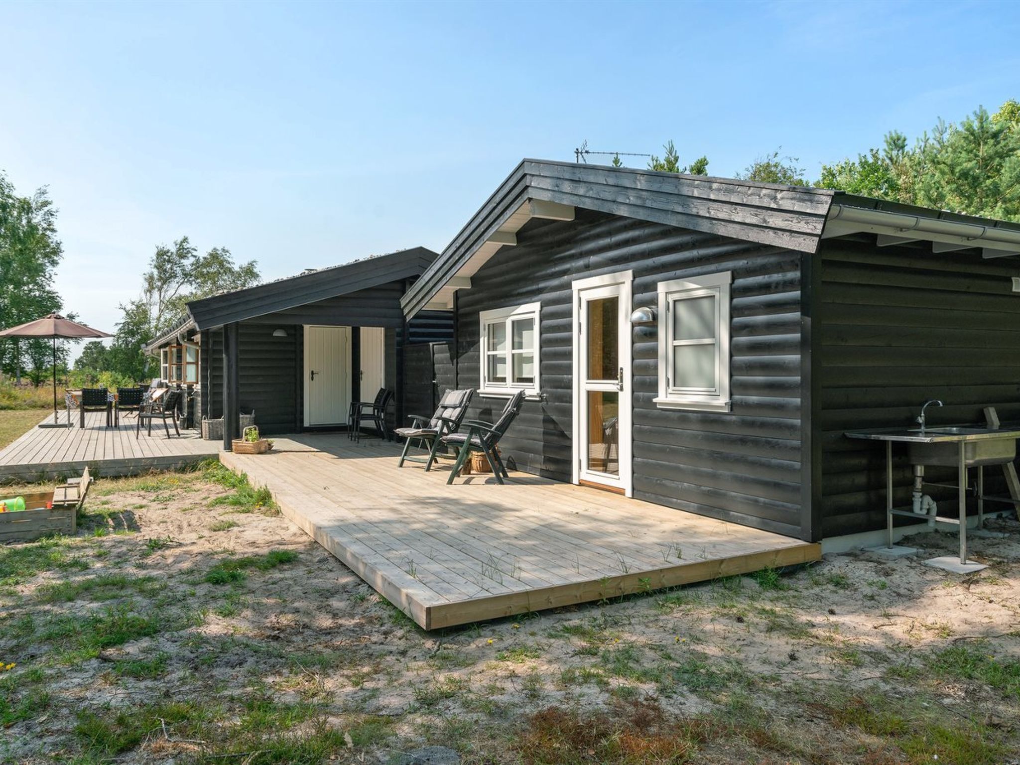 Une cabane dotée d’une terrasse, d’un espace salon extérieur et d’un petit coin cuisine.