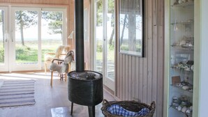 Une pièce chaleureuse avec un grand poêle noir, un panier en osier, une chaise et une étagère ornée d’objets décoratifs.