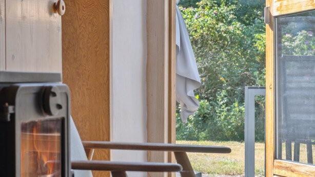 Un camper con interni in legno, un tavolino e una finestra che si affaccia sul verde.