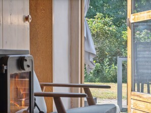 Ein Campingwagen mit Holzinnenraum, einem kleinen Tisch und einem Fenster mit Blick auf Grünflächen.