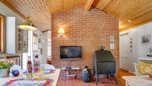 A cozy living area with a brick fireplace, a flat-screen TV mounted on the wall, and a wooden ceiling. - "Mirla" - 300m from the sea by Interhome (Læsø)