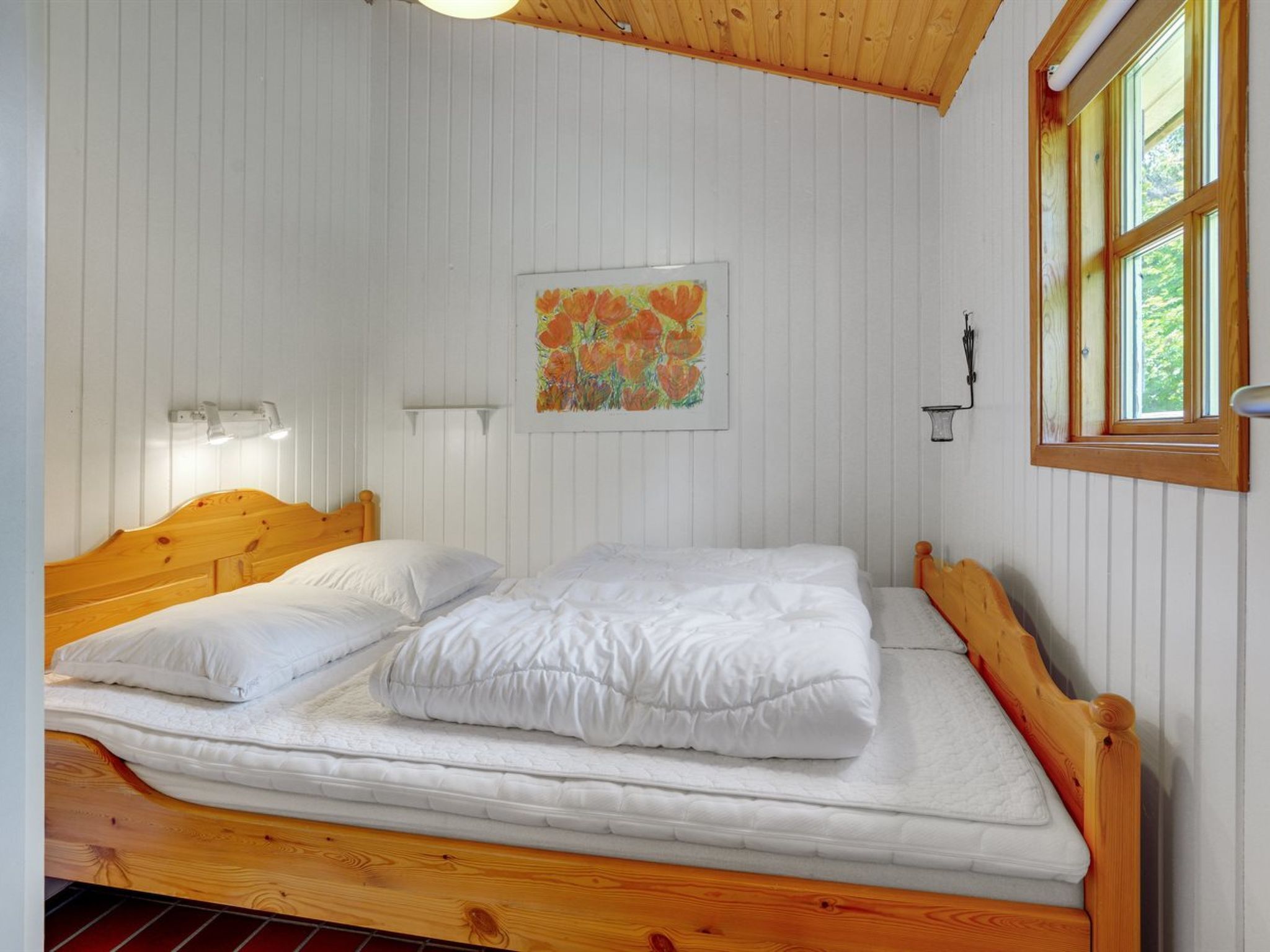 Ein Einzelbett mit weißer Bettwäsche in einem Zimmer mit Holzwänden und Holzboden.