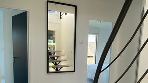 Et moderne interiør med trappe, et stort spejl og udsigt til et soveværelse.