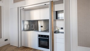 Una cocina compacta con horno integrado, refrigerador de acero inoxidable y lavamanos.