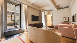 Una sala de estar moderna con un sofá, una televisión y vistas a un edificio de ladrillo a través de una puerta corredera.