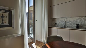 A modern kitchen with a marble backsplash, a built-in oven, and a window with curtains.