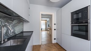 A modern kitchen with a marble backsplash, stainless steel sink, and built-in oven. - Apartments Florence -Palazzo Signoria Luxury Apartments 7-Perseo (FIRENZE)