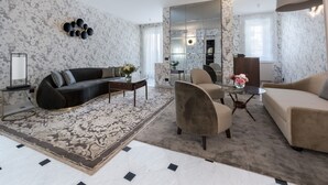 A modern living room with a sofa, armchairs, a coffee table, and a rug.