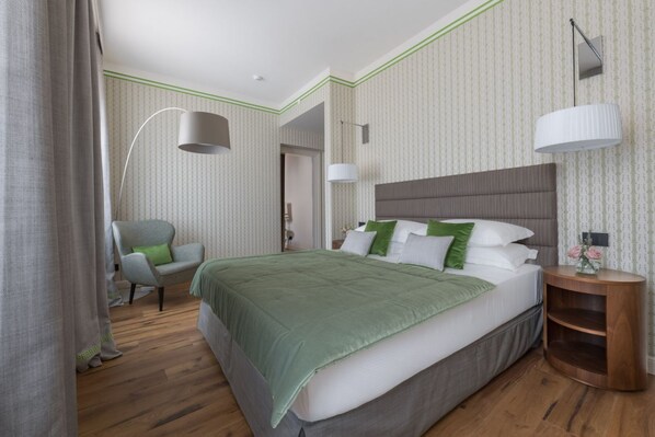 Un dormitorio con una cama grande, una silla, una mesita de noche y una lámpara.