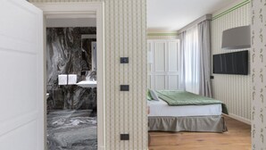 A bedroom with a bed, a TV, and a bathroom visible through an open door.