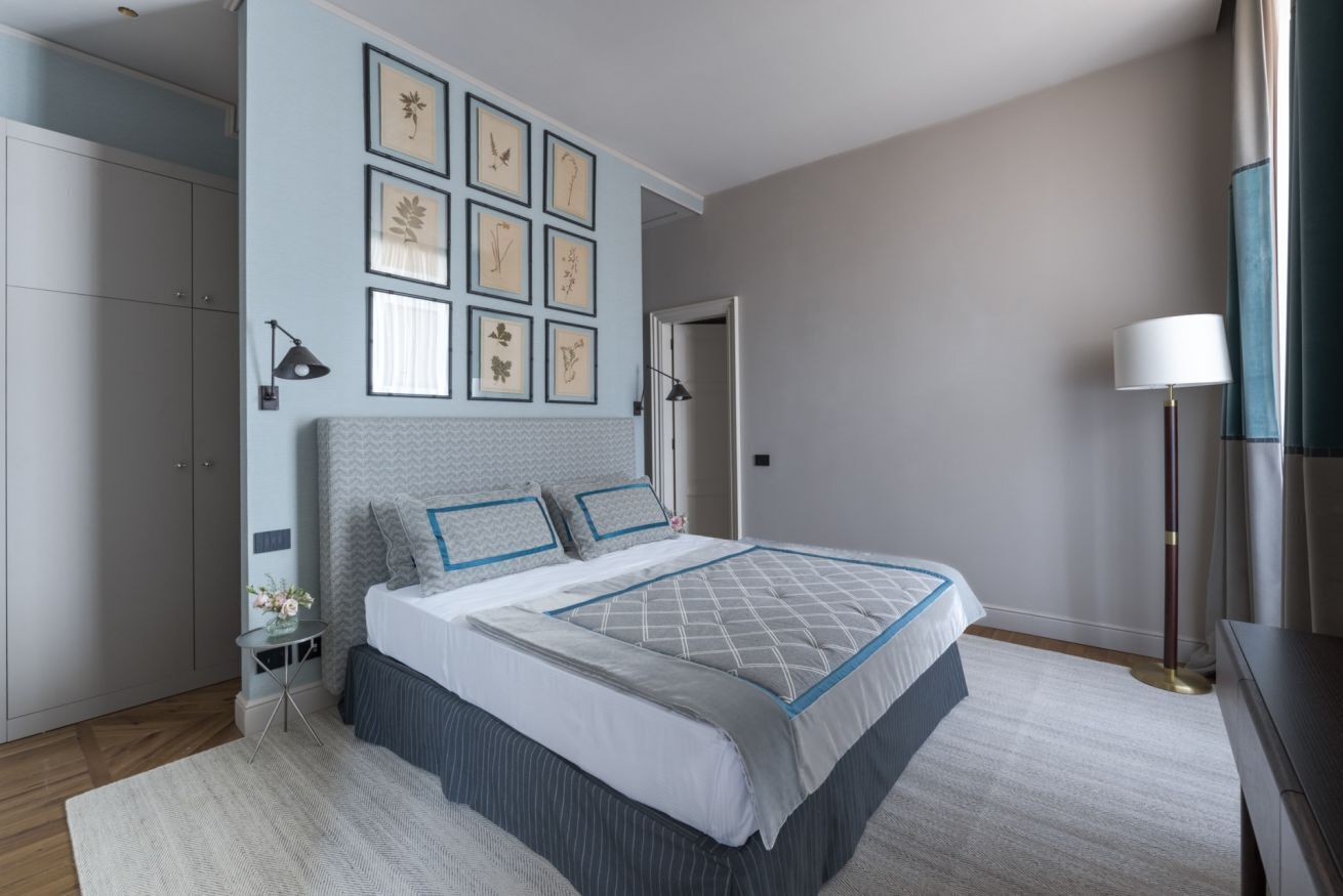 Quarto com uma cama, quadros nas paredes, uma mesa de cabeceira e uma luminária.