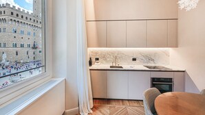 Une cuisine moderne dotée de plans de travail en marbre, d’un four encastré et offrant une vue sur un bâtiment historique par le biais d’une fenêtre.