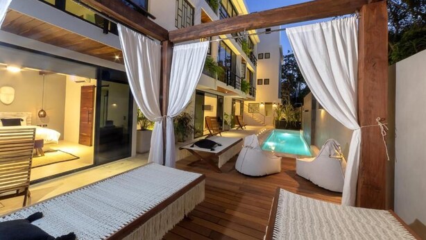 Un'area relax esterna moderna con piscina, terrazza in legno e zone salotto.