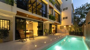 Un edificio moderno a più piani con piscina, area relax all'aperto e piante in vaso.