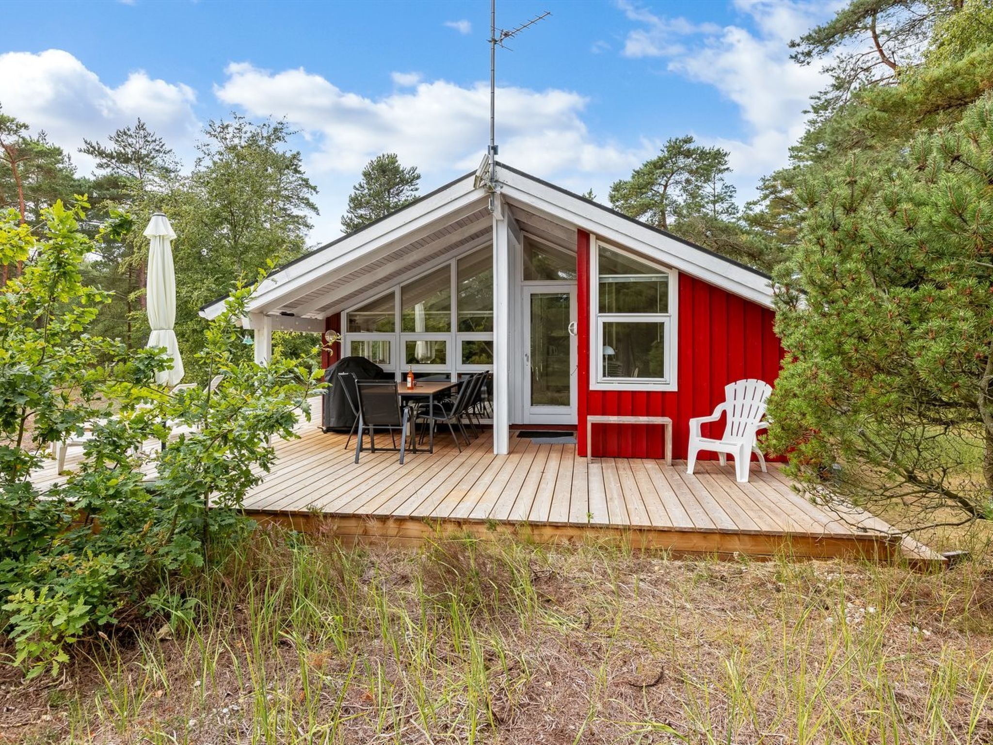 A small cabin with a wooden deck, a dining table, and a grill.