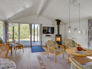 Ein gemütliches Wohnzimmer mit Kamin, Korbmöbeln und einem Fernseher.