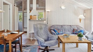 Ein gemütliches Wohnzimmer mit einem Holzespeisekammer, zwei grauen Sesseln, einem Couchtisch aus Holz und einem farbenfrohen Teppich.