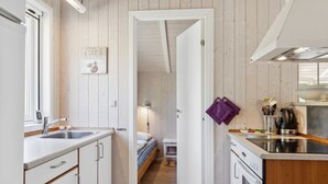 Eine kleine Küche mit Holzboden, einem Bett im Hintergrund und einem Schild mit der Aufschrift 'CAFE'.