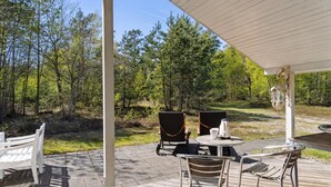 Eine Terrasse im Freien mit Tisch und Stühlen, umgeben von bewaldetem Gelände.