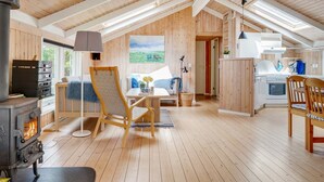 Ein gemütliches Blockhaus mit Holzvertäfelung, einem Essbereich, einer Küche und einem Kamin.