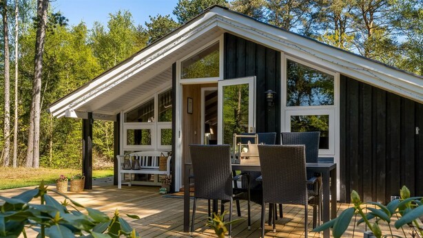 Eine Holzterrasse mit Essbereich, einer Bank und Topfpflanzen.