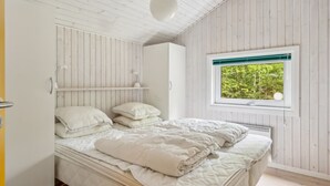 Un dormitorio con cama, ventana con vista a zonas verdes y paredes de madera.