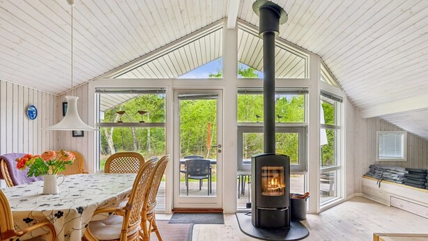 Una habitación acogedora con un ventanal grande, una mesa con sillas, chimenea y vistas al exterior.