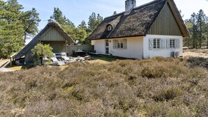 A rustic cabin with a thatched roof, a wooden deck, and a small garden area. - "Gravers" - 300m from the sea by Interhome (Læsø)