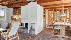A rustic interior with exposed wooden beams, a fireplace, a dining area, and a kitchen with wooden cabinets. - "Gravers" - 300m from the sea by Interhome (Læsø)