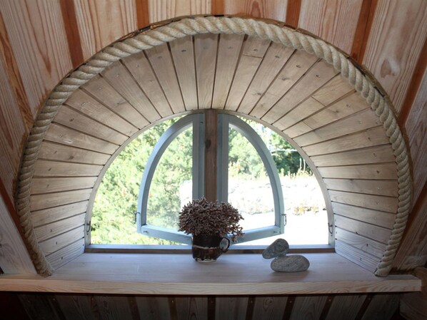 A wooden arched window with a potted plant and two stones on a shelf.