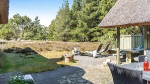 A patio area with a thatched-roof structure, outdoor seating, and a stone pathway. - "Gravers" - 300m from the sea by Interhome (Læsø)